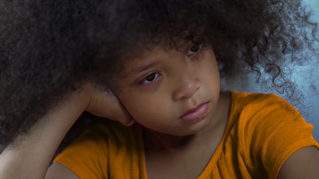 Sad curly female African American kid sitting alone